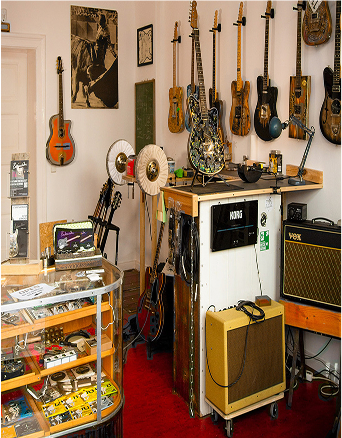 Ein Instrumenten Geschäft mit verschiedenen Guitarren, Lautsträrkern und Postern.